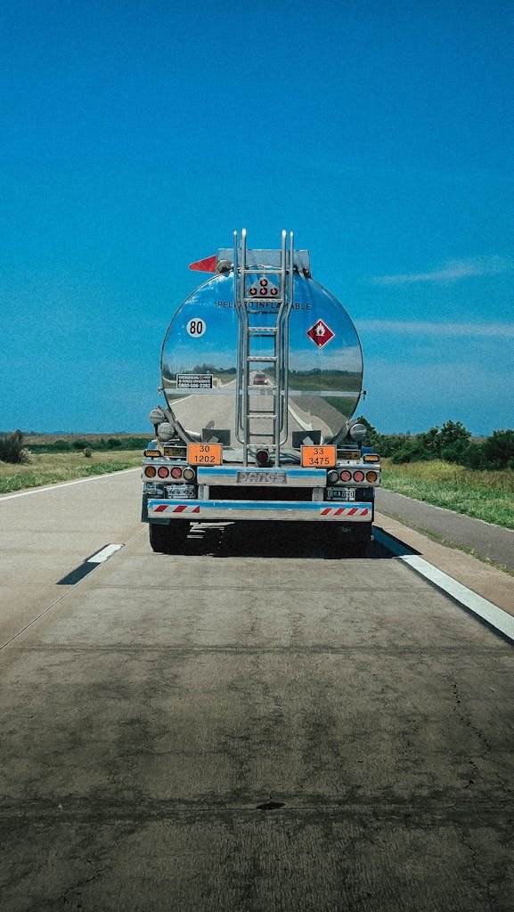 A fuel tanker truck travels along a highway under clear blue skies in Argentina.